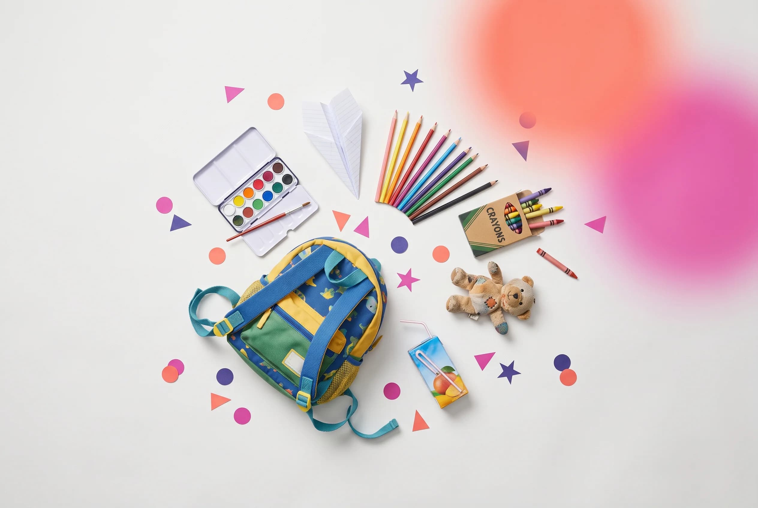 Ilustración cenital tipo flat-lay de una mochila infantil azul y verde, acuarelas, lápices de colores, ceras, un peluche de oso y un avión de papel, sobre fondo claro con confeti de papel coral y magenta y un resplandor degradado en la esquina